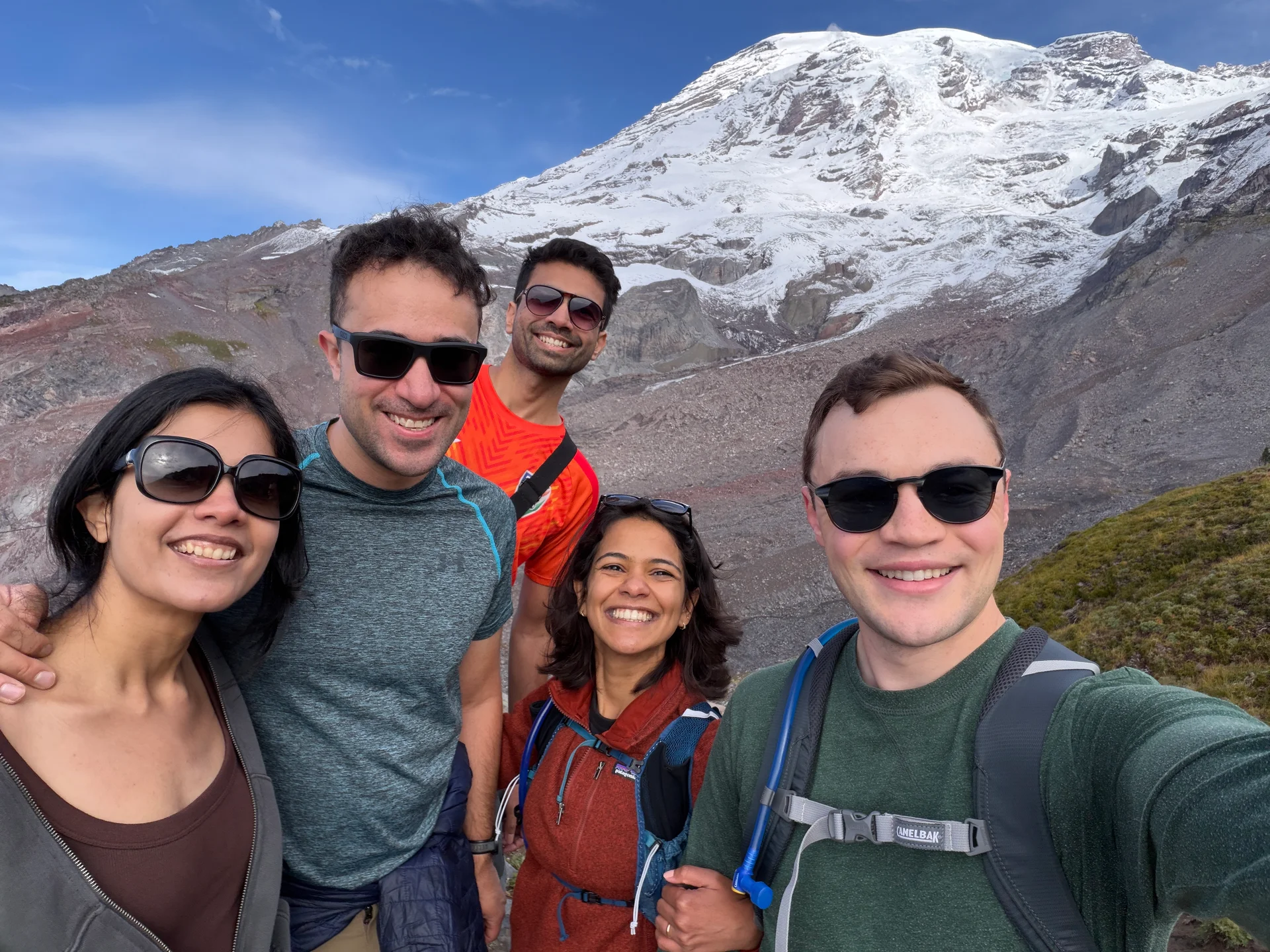 Five of the group smiling on the Skyline Loop with Rainier filling the sky behind them