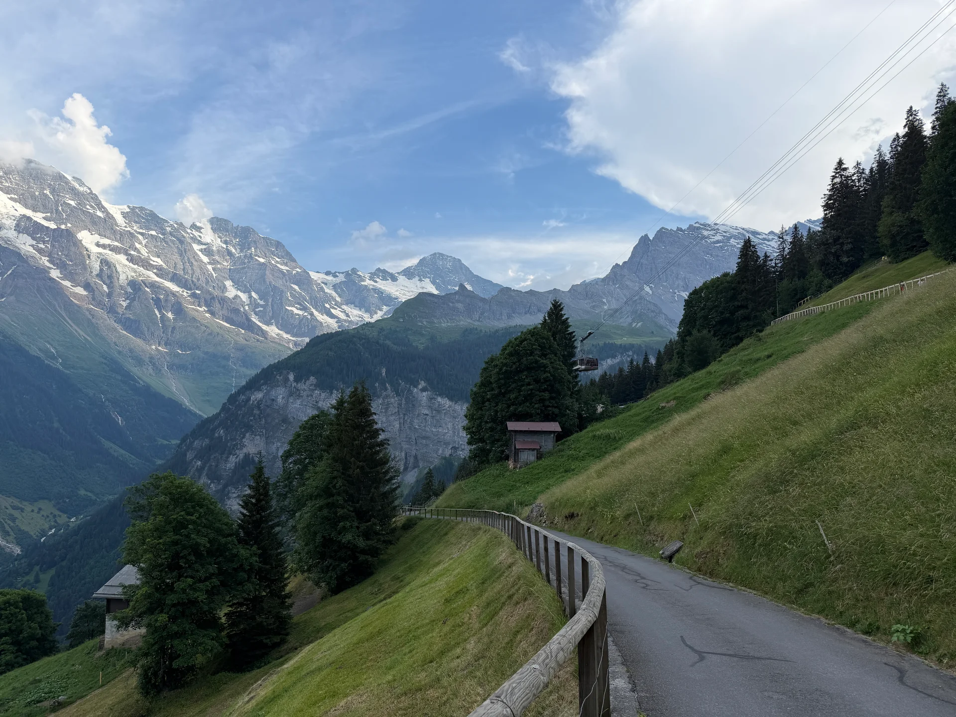 A quiet mountain road into Mürren with snow-capped Alps behind